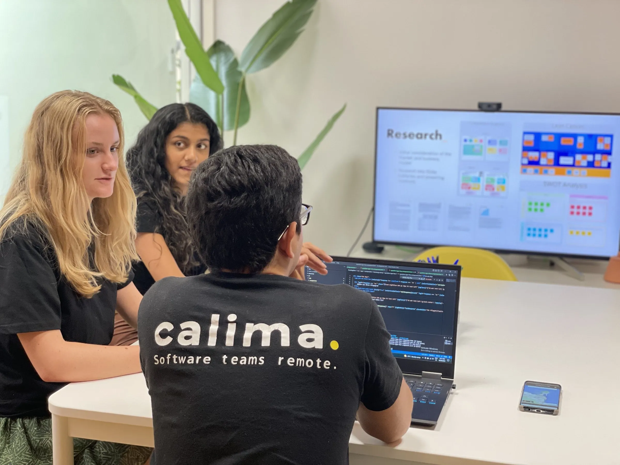 Three Calima team members in a project meeting, with research results on the screen